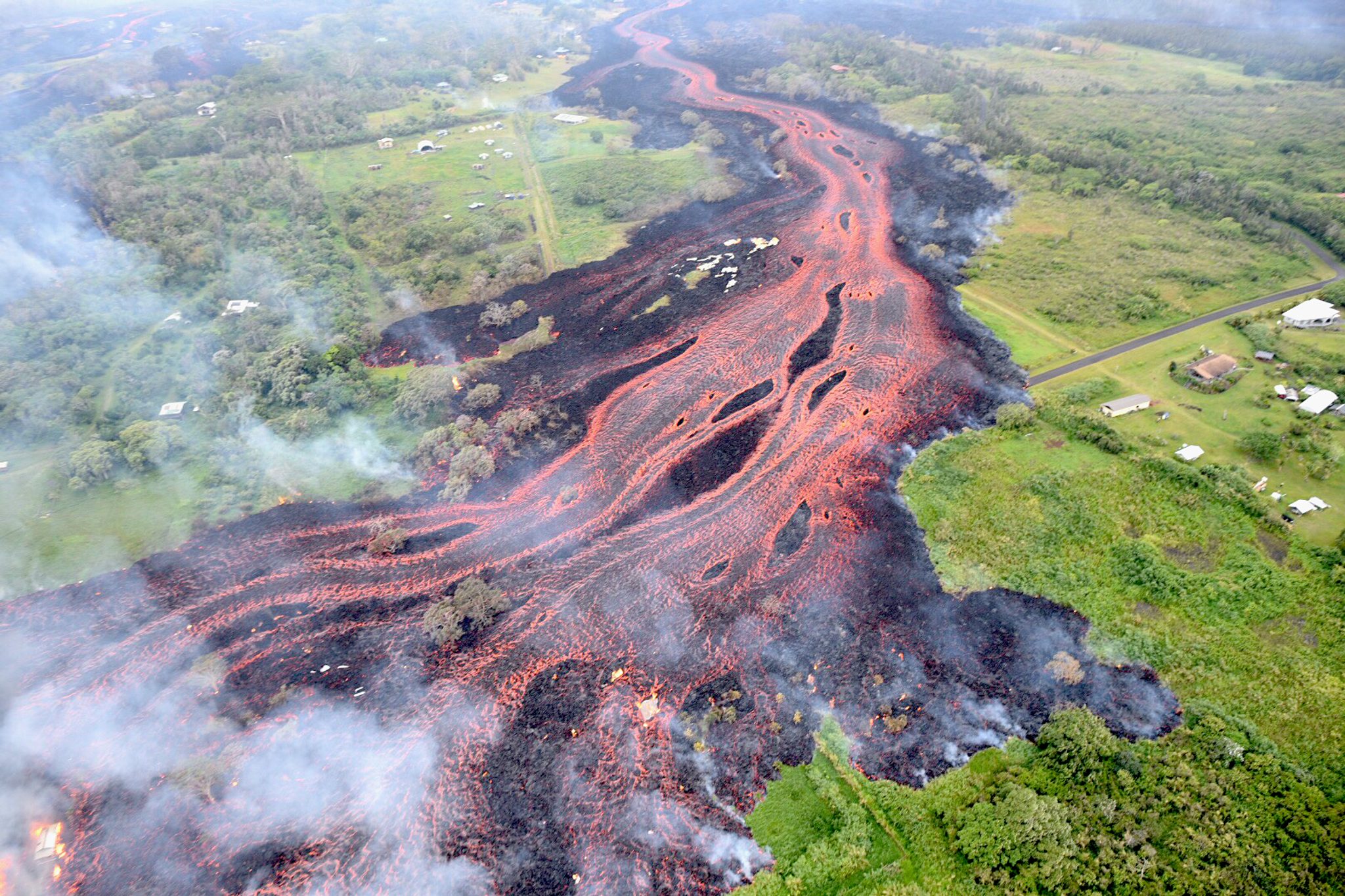 Molten ʻaʻā lava flows channeling across dark ground during the 2018 eruption of Kīlauea on Hawaiʻi Island.