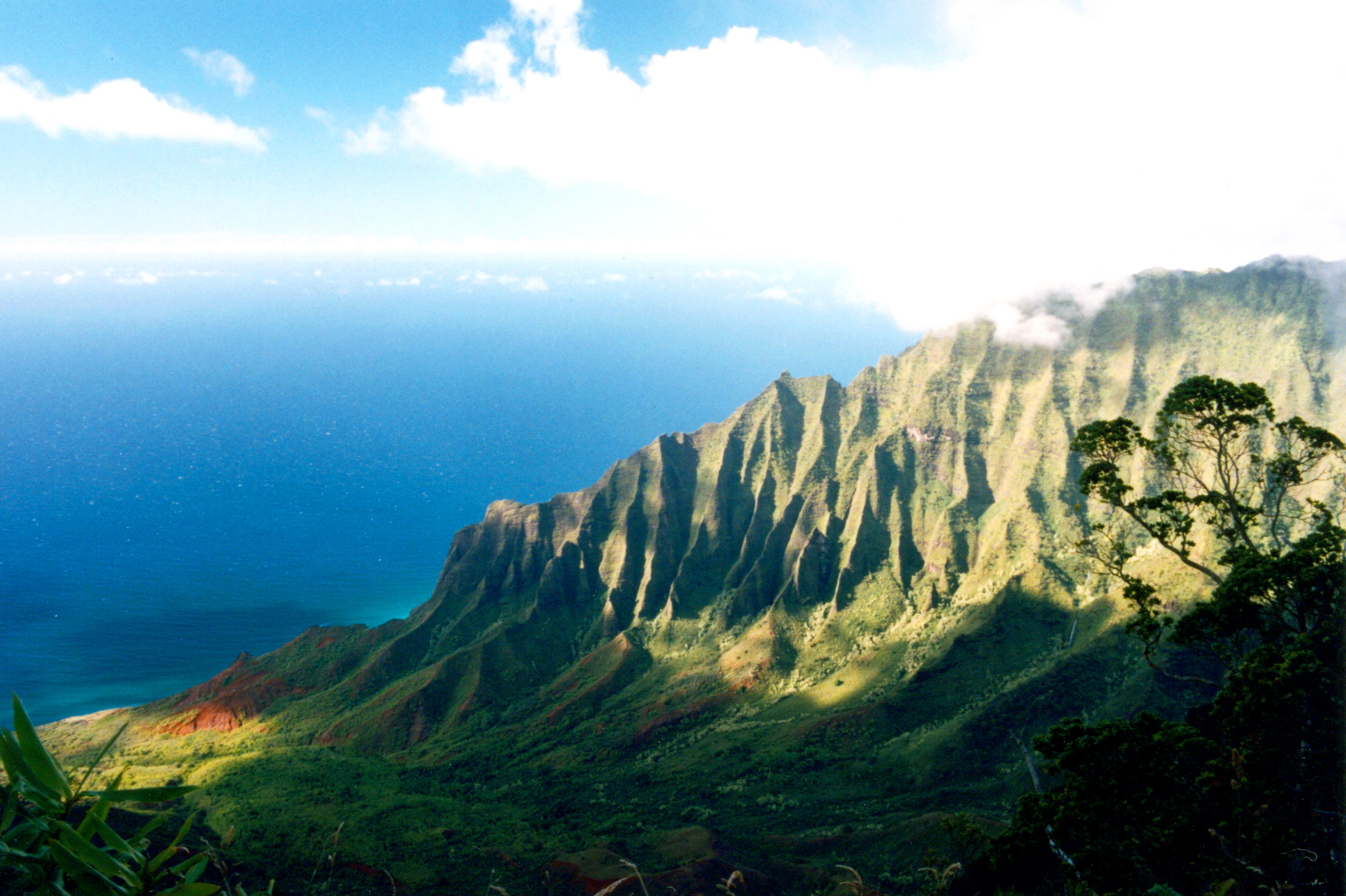 The fluted green cliffs of the Nā Pali Coast dropping to the ocean on Kauaʻi.